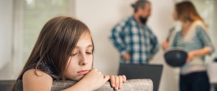 enfant accoudée avec sa famille qui se dispute en arrière-plan