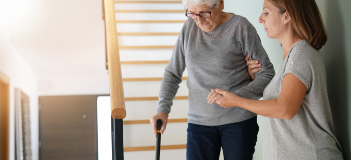 Une femme aide une autre femme plus âgée à descendre les escaliers d'une maison