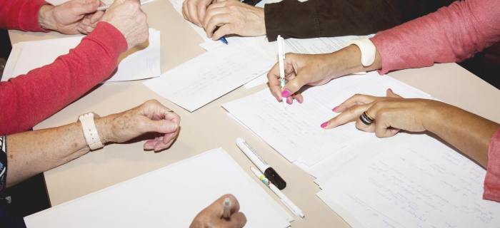 Des mains de plusieurs personnes remplissent des feuilles de notes © Plateforme seniors