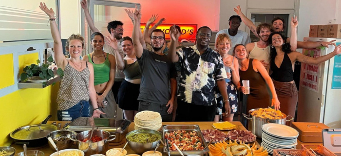 Des jeunes posent dans une cuisine avec différents plats de nourriture devant eux