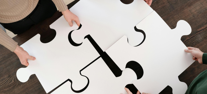 Les mains de 4 personnes assemblent 4 pièces géantes d'un puzzle 