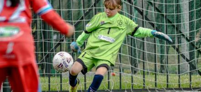 Une jeune gardienne footballeuse dégage la balle au pied