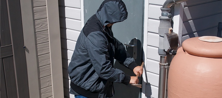 Un voleur essaie de forcer une porte à l'aide d'un pied-de-biche