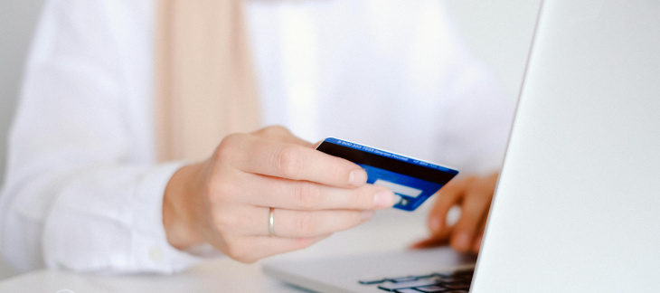 Personne devant un ordinateur portable avec une carte de crédit dans une main