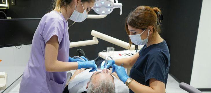 Deux dentistes travaillent sur les dents d'un patient. Creative Commons