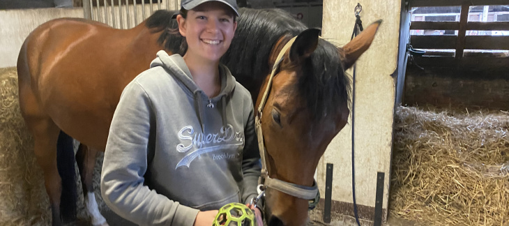 Alicia Rivolet, apprentie gardienne de chevaux, en compagnie d'un cheval devant un box