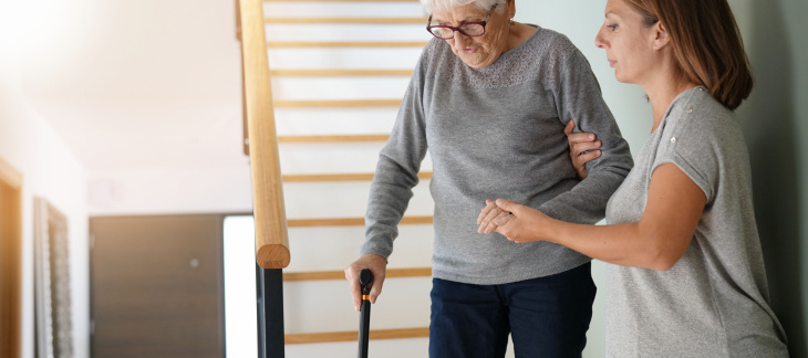 Une femme aide une autre femme plus âgée à descendre les escaliers d'une maison