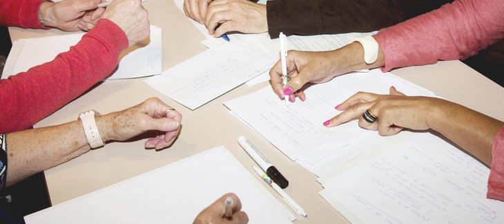 Des mains de plusieurs personnes remplissent des feuilles de notes © Plateforme seniors