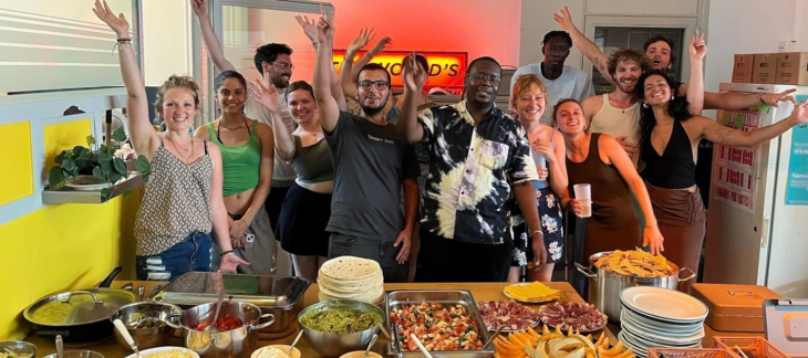 Des jeunes posent dans une cuisine avec différents plats de nourriture devant eux