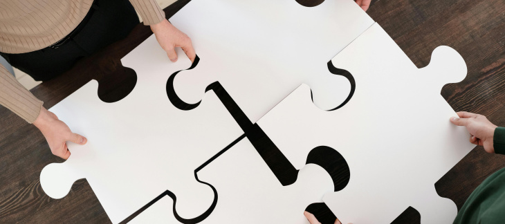 Les mains de 4 personnes assemblent 4 pièces géantes d'un puzzle 