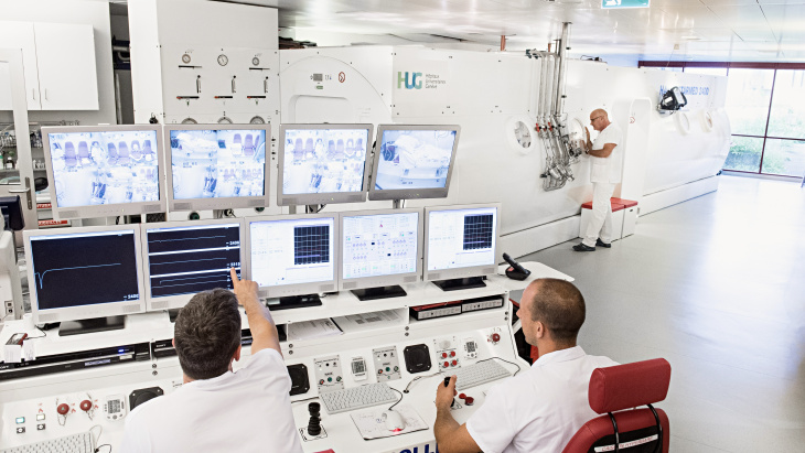 Deux médecins surveillent des patients en caisson hyperbare, aux Hôpitaux Universitaires de Genève (HUG) - ©HUG