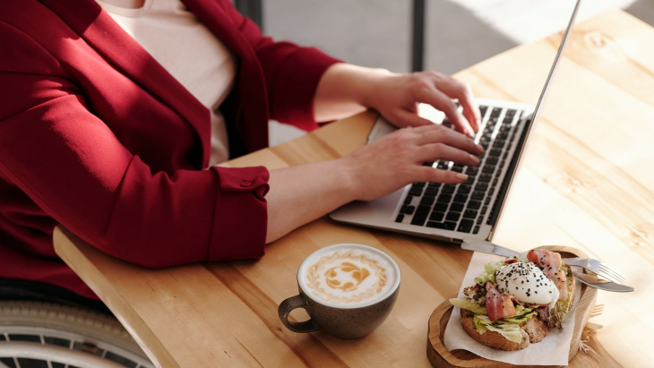 femme devant l'ordinateur avec un café et un sandwich