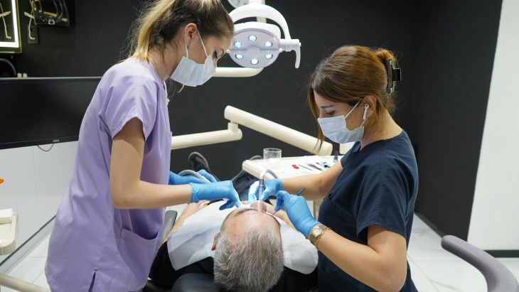 Deux dentistes travaillent sur les dents d'un patient. Creative Commons