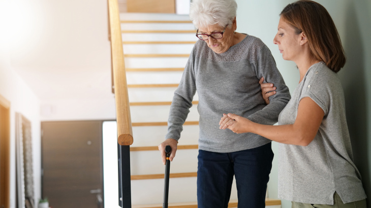 Une femme aide une autre femme plus âgée à descendre les escaliers d'une maison