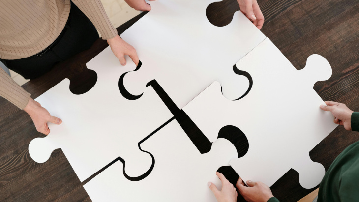 Les mains de 4 personnes assemblent 4 pièces géantes d'un puzzle 