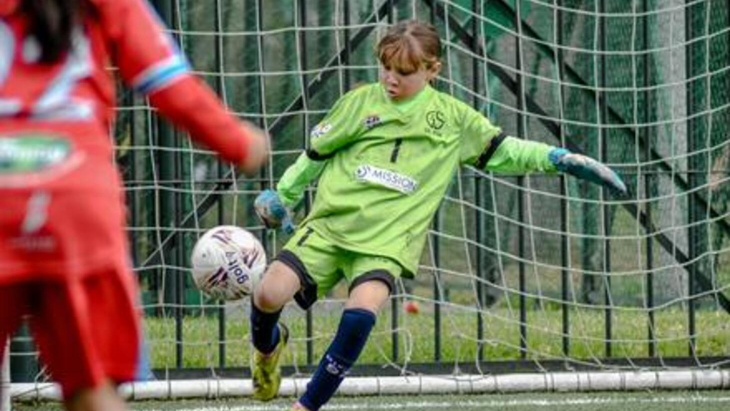 Une jeune gardienne footballeuse dégage la balle au pied