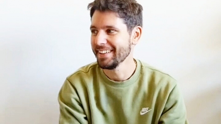 Homme avec un pull vert entrain de sourire 